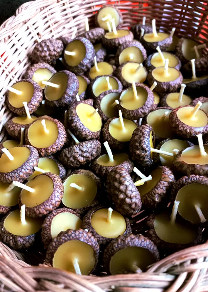 een mandje met bijenwas drijf kaarsjes in eikeldopjes