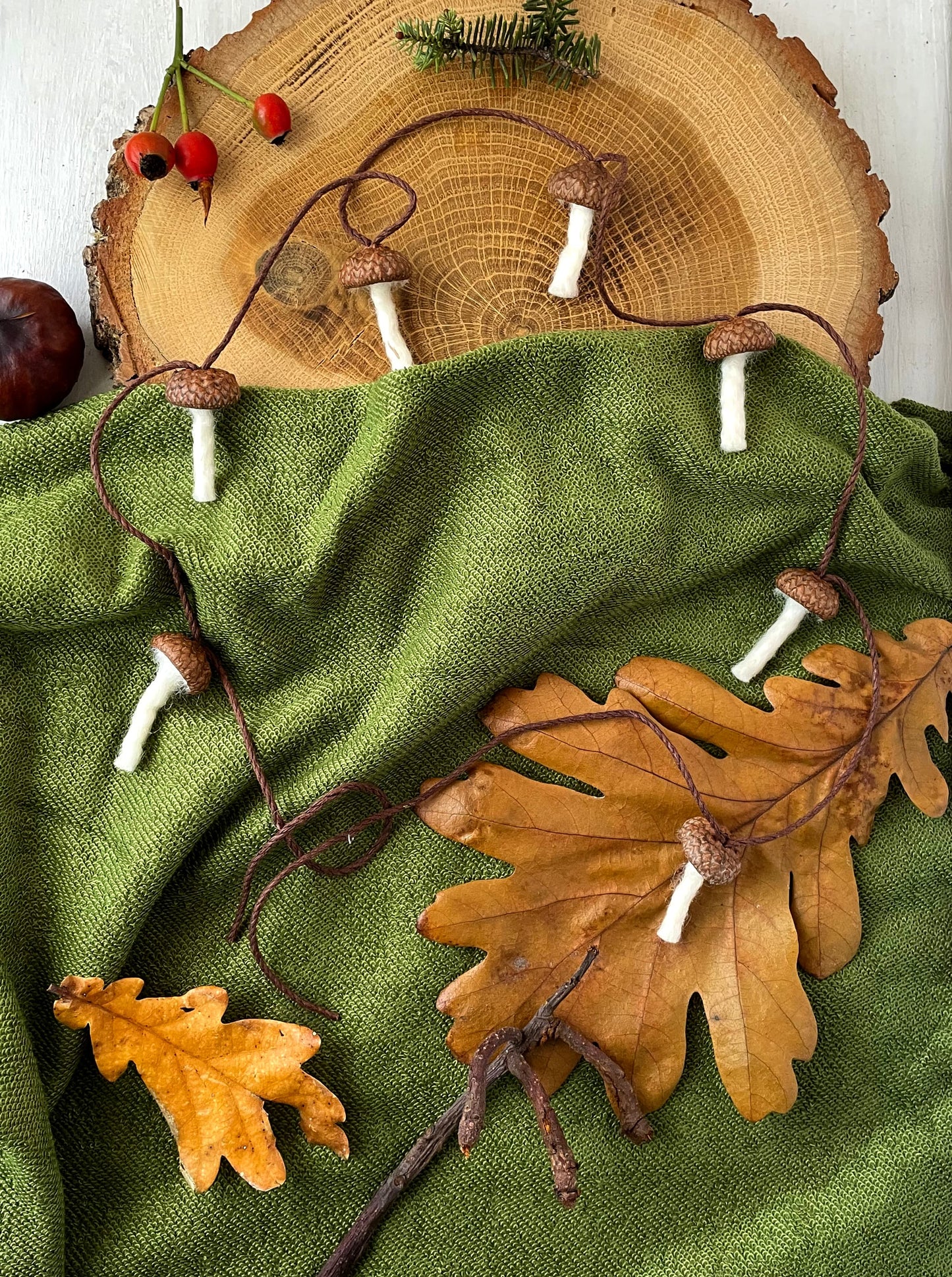 paddenstoelen slinger met eikelhoedjes en gevilte steeltjes op groene doek
